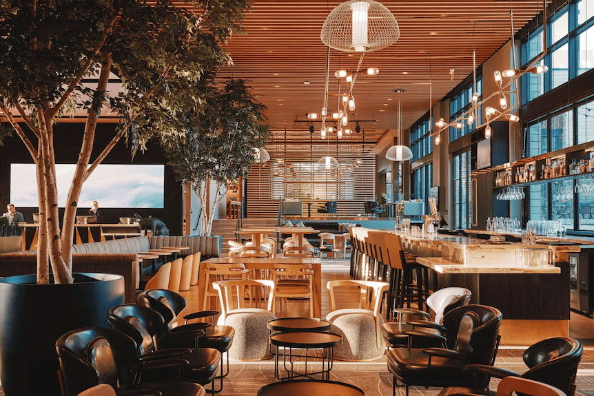 Warm wood-lined lobby and restaurant at Limelight Boulder with seating, trees, and a long bar