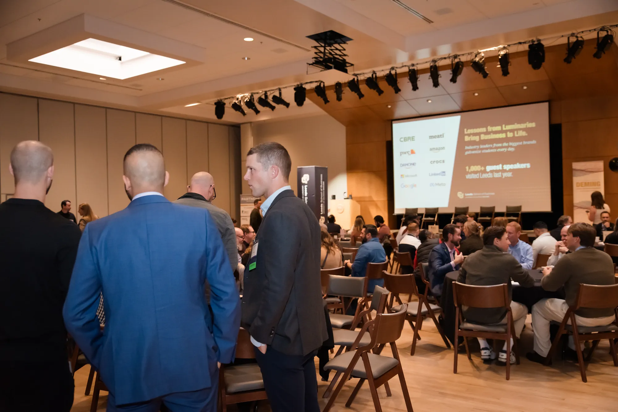 Attendees standing and talking in groups before a session begins