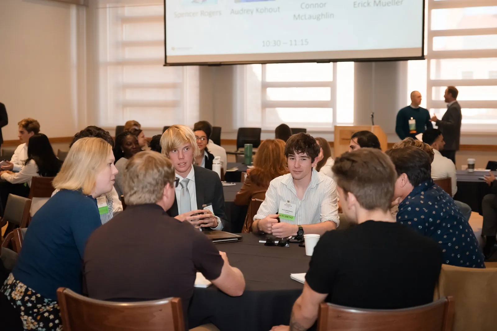 A small group of attendees leaning in around a table in conversation